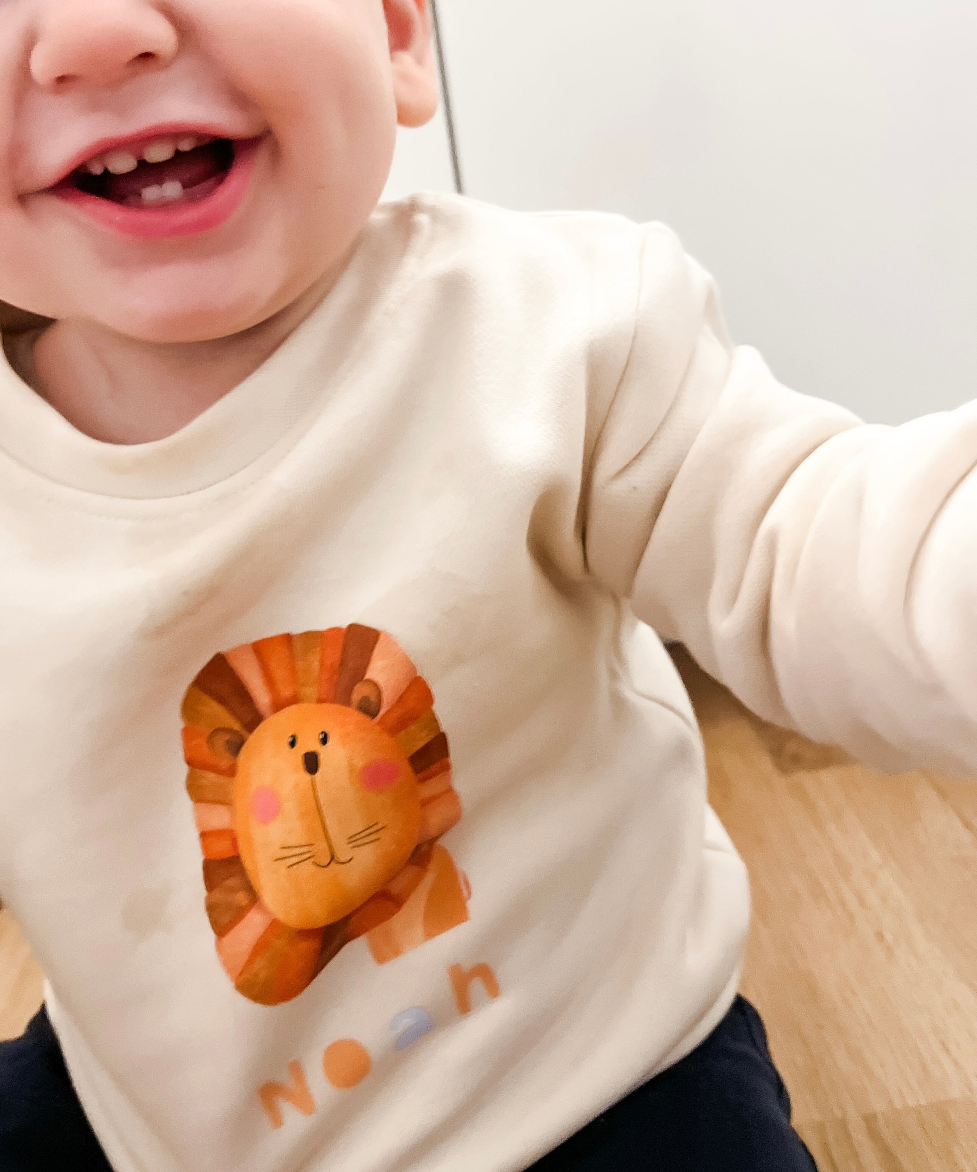 Child wearing a white shirt with a lion graphic and 'Noah' text.